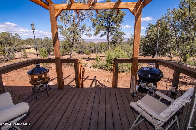 wooden terrace with an outdoor fire pit and a grill