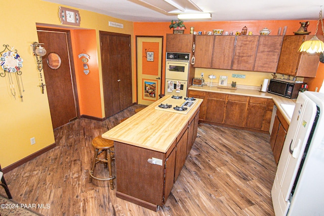 kitchen featuring white appliances, butcher block counters, baseboards, dark wood-style floors, and brown cabinetry