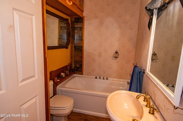 bathroom featuring a sink, toilet, a bath, and wallpapered walls