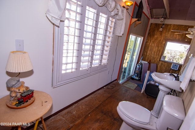 bathroom featuring toilet, wooden walls, and a sink