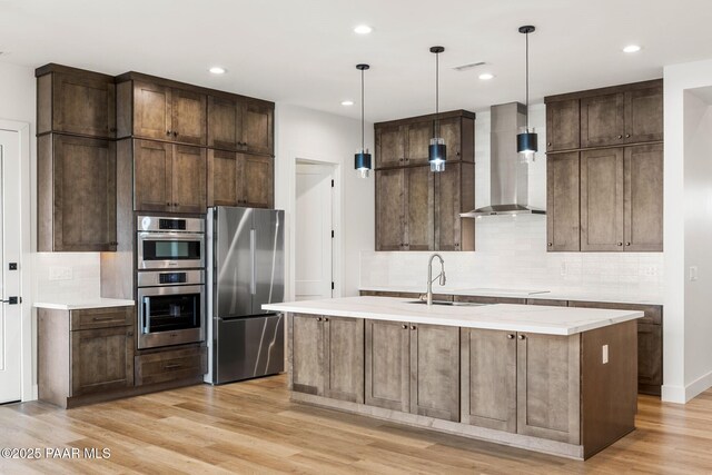 1148 S Lakeview Dr, Prescott, AZ 86301 - kitchen with light wood-style flooring, a sink, appliances with stainless steel finishes, wall chimney exhaust hood, and backsplash