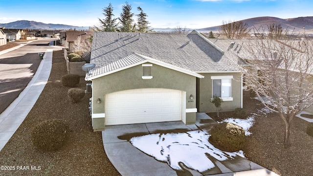 view of front of home featuring a garage, roof with shingles, a mountain view, and stucco siding