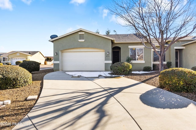 ranch-style house featuring a garage, concrete driveway, and stucco siding