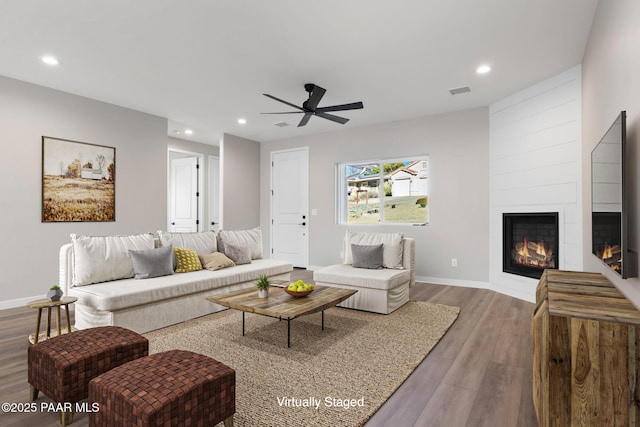 living area with visible vents, wood finished floors, recessed lighting, a large fireplace, and baseboards