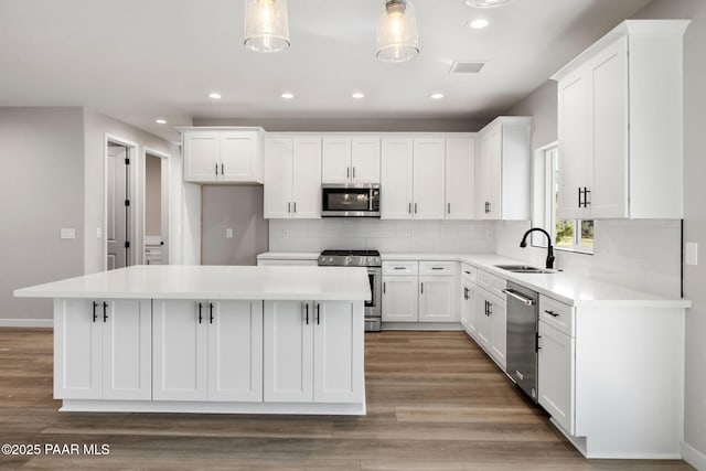 kitchen with visible vents, a sink, decorative backsplash, appliances with stainless steel finishes, and a center island