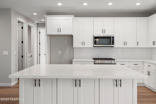 kitchen with stainless steel microwave, range, light wood-type flooring, and a kitchen island