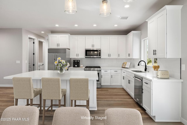 kitchen with visible vents, a kitchen island, a sink, stainless steel appliances, and tasteful backsplash