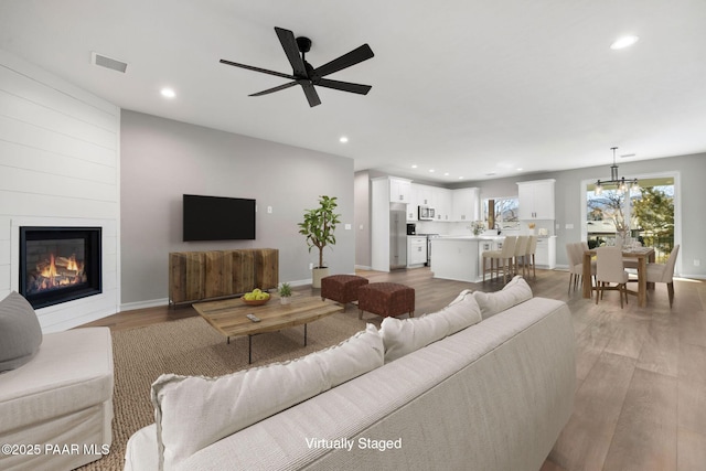 living room with a fireplace, recessed lighting, baseboards, and light wood finished floors