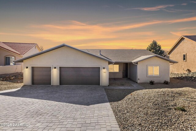 view of front of house with stucco siding, decorative driveway, and a garage