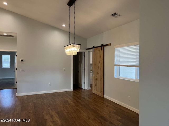 unfurnished dining area featuring a barn door, lofted ceiling, and dark wood-type flooring