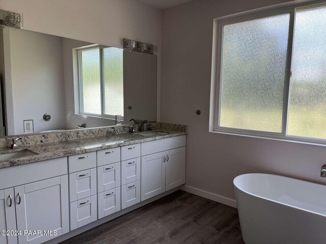 bathroom with a bathtub, vanity, and wood-type flooring