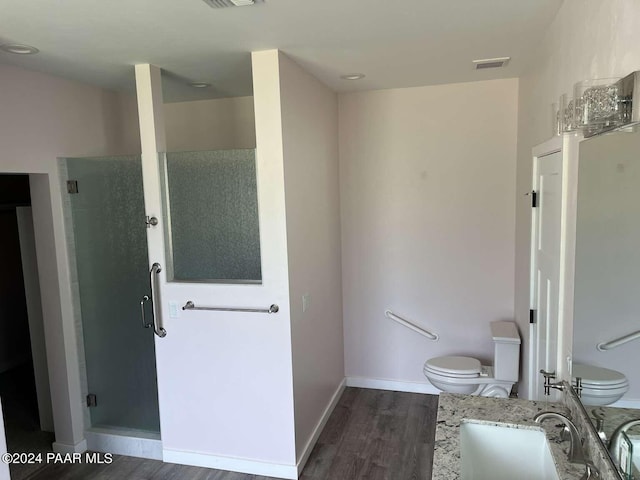 bathroom featuring vanity, hardwood / wood-style flooring, toilet, and a shower with shower door