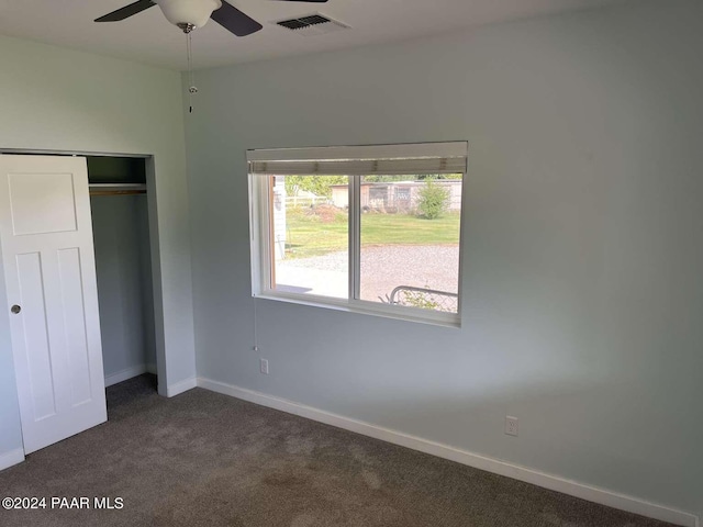 unfurnished bedroom featuring ceiling fan, a closet, and dark carpet