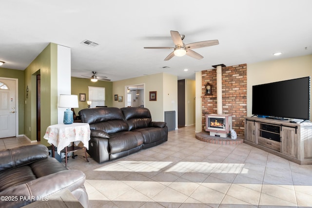 tiled living room with ceiling fan and a wood stove