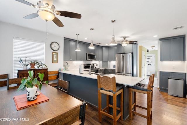 kitchen featuring appliances with stainless steel finishes, decorative light fixtures, sink, kitchen peninsula, and gray cabinetry