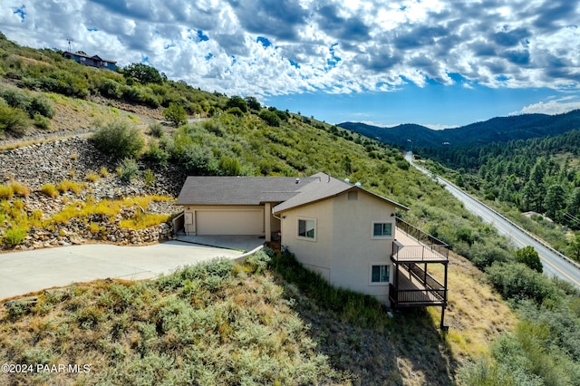 720 E Sky Terrace Dr, Prescott, AZ 86303 - view of property exterior featuring a garage, stucco siding, a deck with mountain view, concrete driveway, and a forest view