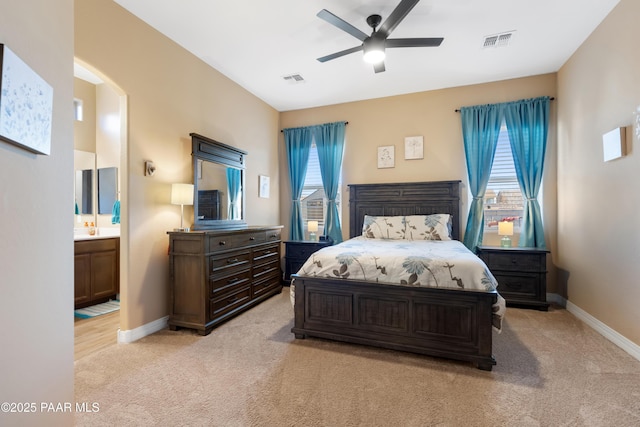 bedroom with connected bathroom, light carpet, and ceiling fan