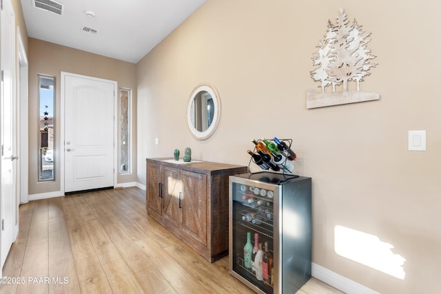 foyer with light hardwood / wood-style floors and beverage cooler