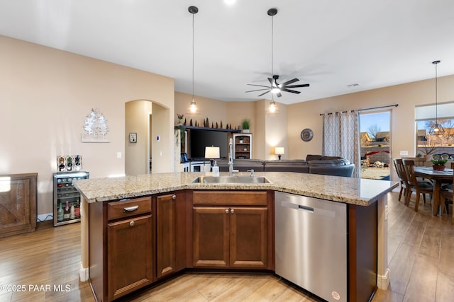 kitchen featuring sink, an island with sink, stainless steel dishwasher, and decorative light fixtures