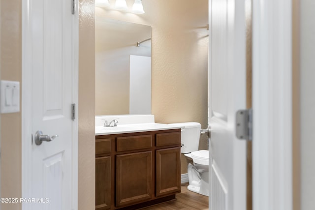 bathroom with hardwood / wood-style floors, vanity, and toilet