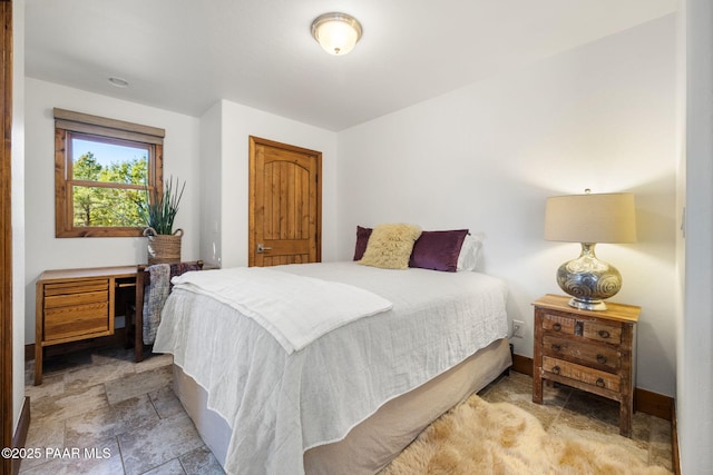 bedroom with baseboards and stone finish flooring