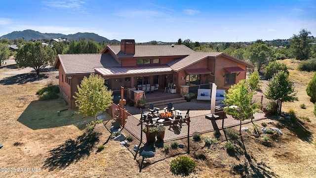 back of property with outdoor lounge area, a tiled roof, a patio area, and a mountain view