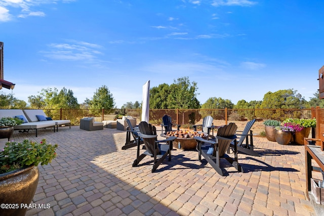 view of patio with an outdoor living space with a fire pit and fence