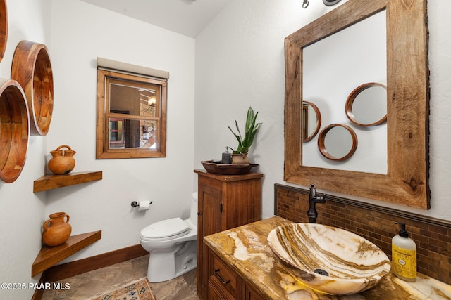 bathroom featuring vanity, toilet, and baseboards