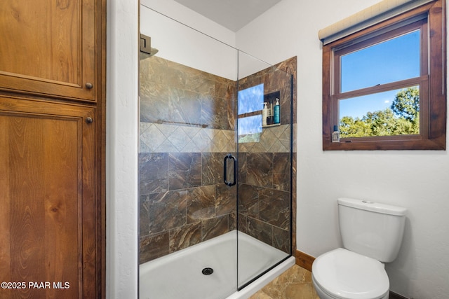 bathroom featuring a shower stall, toilet, and baseboards