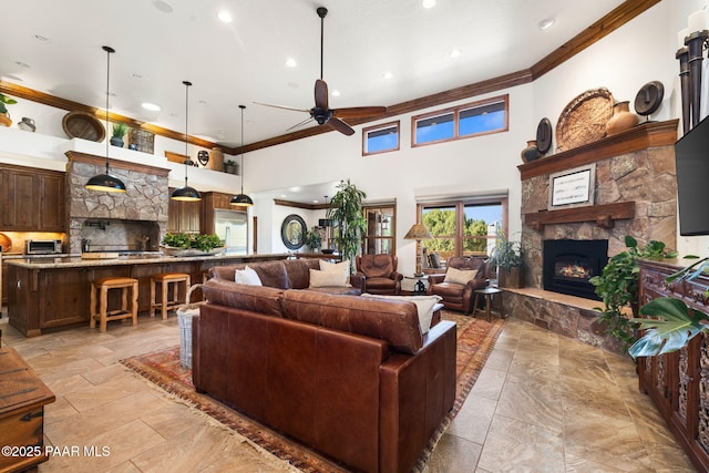 living room featuring ornamental molding, a fireplace, and ceiling fan