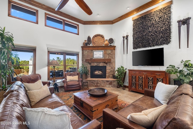 living area with a high ceiling, a fireplace, crown molding, and ceiling fan