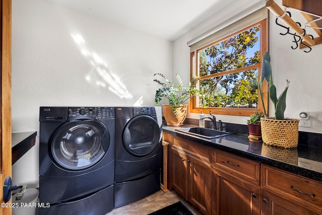 washroom with cabinet space, washing machine and dryer, and a sink