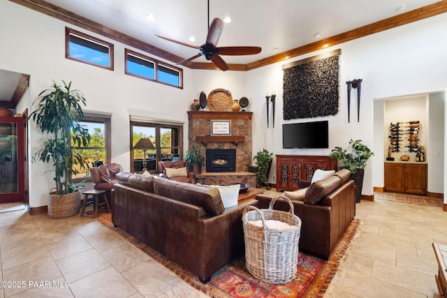 living room with baseboards, a fireplace, ornamental molding, and a ceiling fan