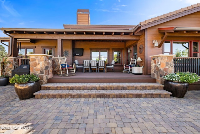 rear view of property featuring covered porch and a chimney