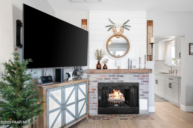 living area with a brick fireplace and light wood-style floors