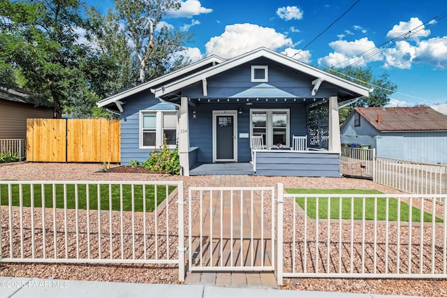 bungalow featuring a fenced front yard, covered porch, and a gate