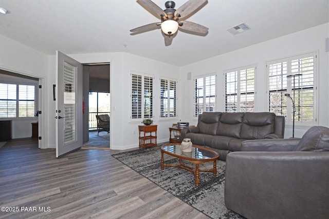 living area with wood finished floors, a ceiling fan, visible vents, and baseboards