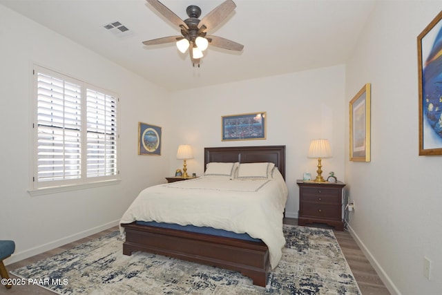 bedroom featuring wood finished floors, visible vents, a ceiling fan, and baseboards