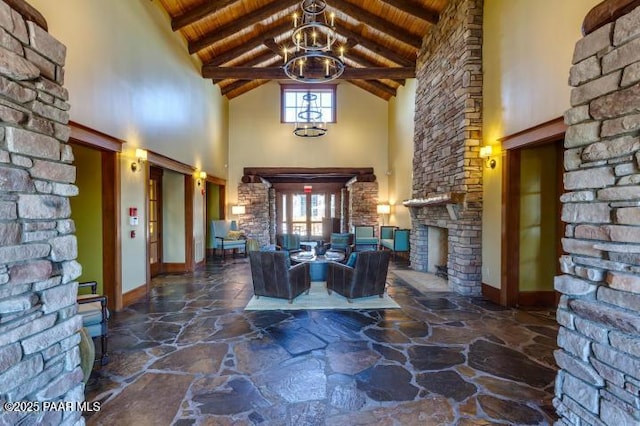 interior space with stone flooring, wooden ceiling, an inviting chandelier, beam ceiling, and high vaulted ceiling