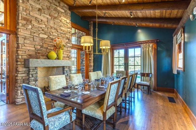 dining room with wood-type flooring, plenty of natural light, beam ceiling, and wood ceiling