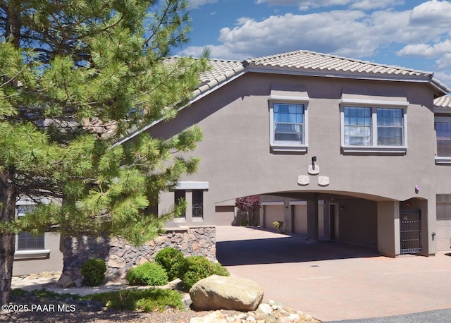 view of front of home with driveway, a garage, stucco siding, and a tiled roof