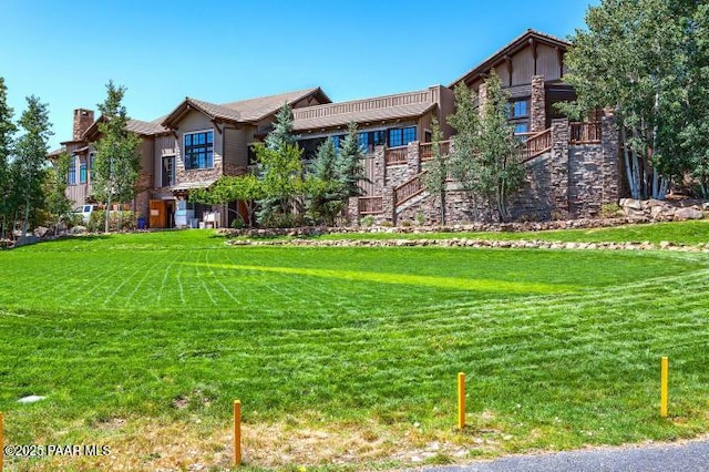 exterior space featuring a front lawn, stairs, stone siding, and a chimney