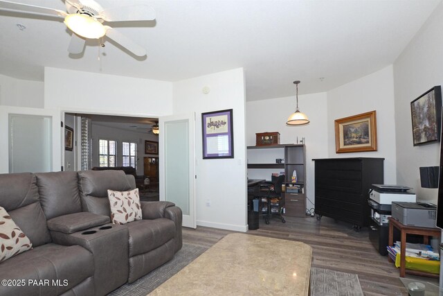 living room featuring dark wood finished floors, baseboards, and a ceiling fan