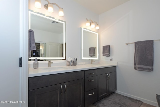 bathroom featuring baseboards, double vanity, and a sink