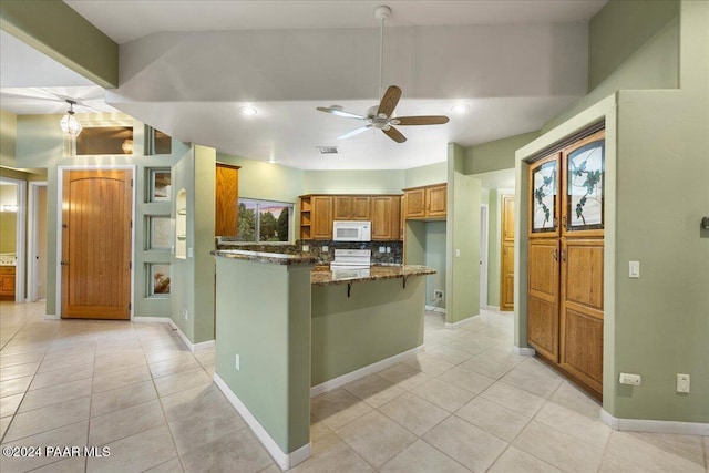 kitchen with ceiling fan, tasteful backsplash, dark stone counters, white appliances, and light tile patterned floors