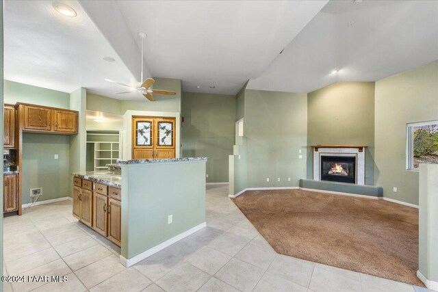 kitchen featuring light tile patterned floors, light stone counters, and ceiling fan