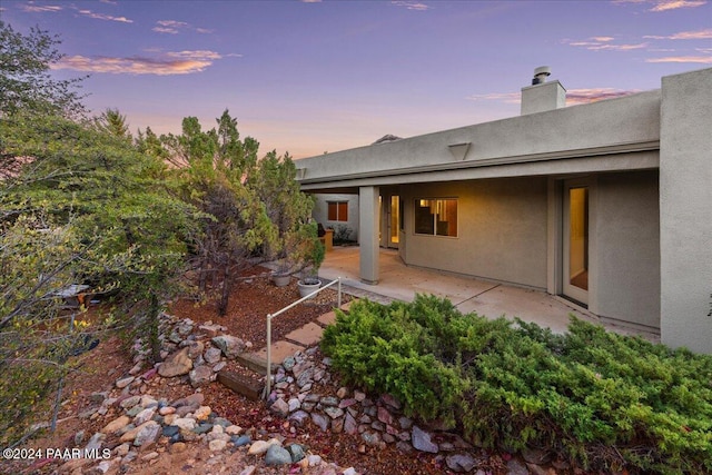 back house at dusk featuring a patio area