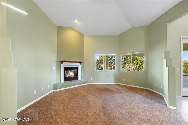 unfurnished living room with light carpet and vaulted ceiling