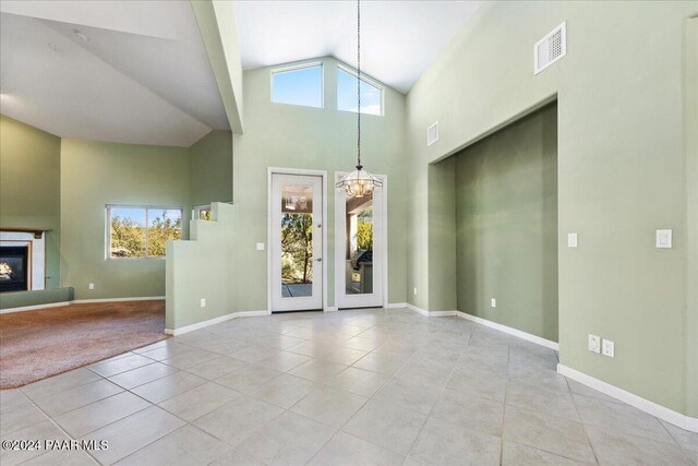 foyer with light tile patterned floors, high vaulted ceiling, and a chandelier