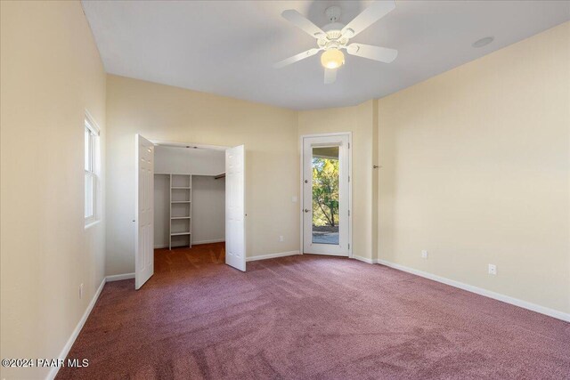 unfurnished bedroom with carpet flooring, access to exterior, a walk in closet, ceiling fan, and a closet